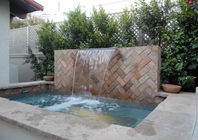 Multi level backyard with cascade waterfall, spa, built-in seating, patio, and firepit.