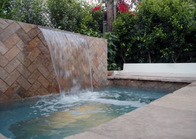 Multi level backyard with cascade waterfall, spa, built-in seating, patio, and firepit.