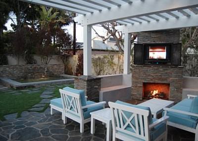 Outdoor living room with fireplace, synthetic grass, and spa